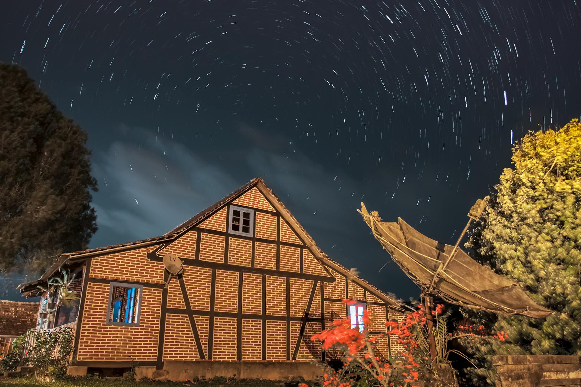Casa em estilo enxaimel sob céu estrelado com efeito de rastros de estrelas à noite em Pomerode, Santa Catarina