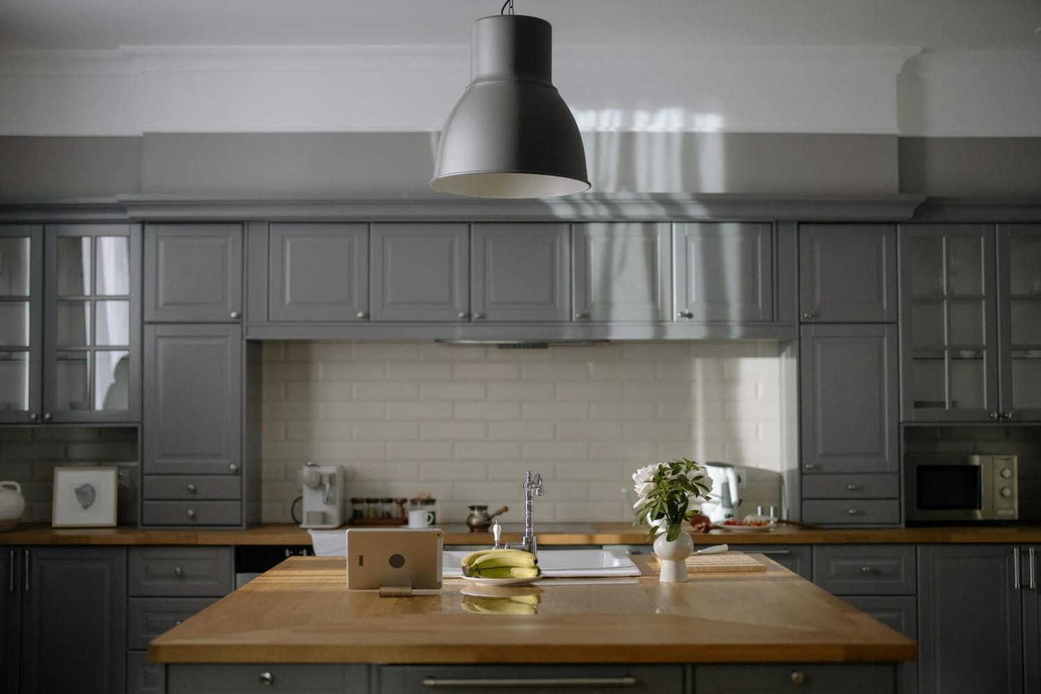 Cozinha planejada com armários cinza, revestimento cerâmico branco na parede e diferentes acabamentos