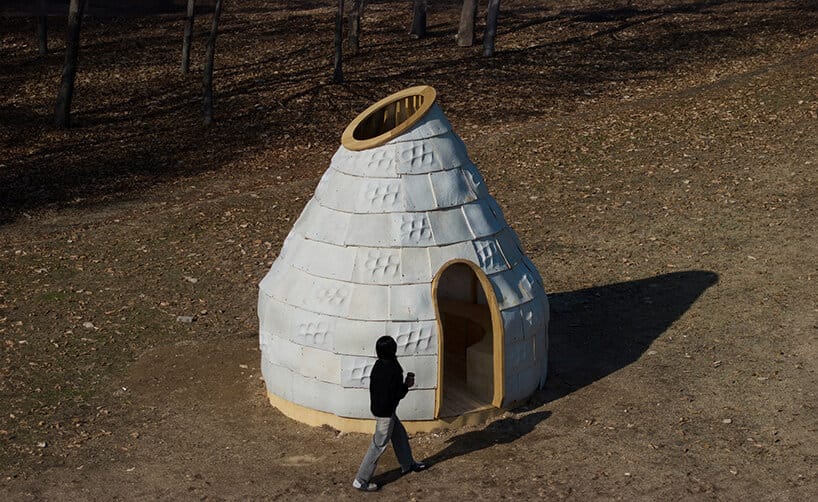 Pavilhão cônico de blocos de micélio branco com óculo superior, num parque em Seul