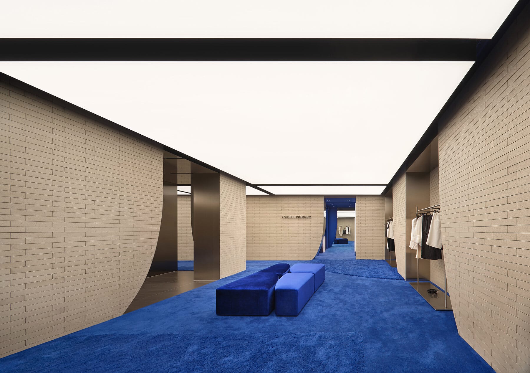 Interior da loja com paredes de tijolo cinza claro e carpete azul