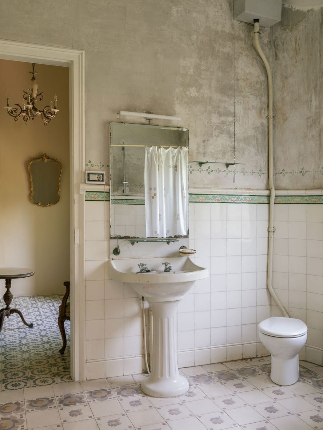 Banheiro original preservado, com pia de louça, azulejo antigo e piso de ladrilho hidráulico