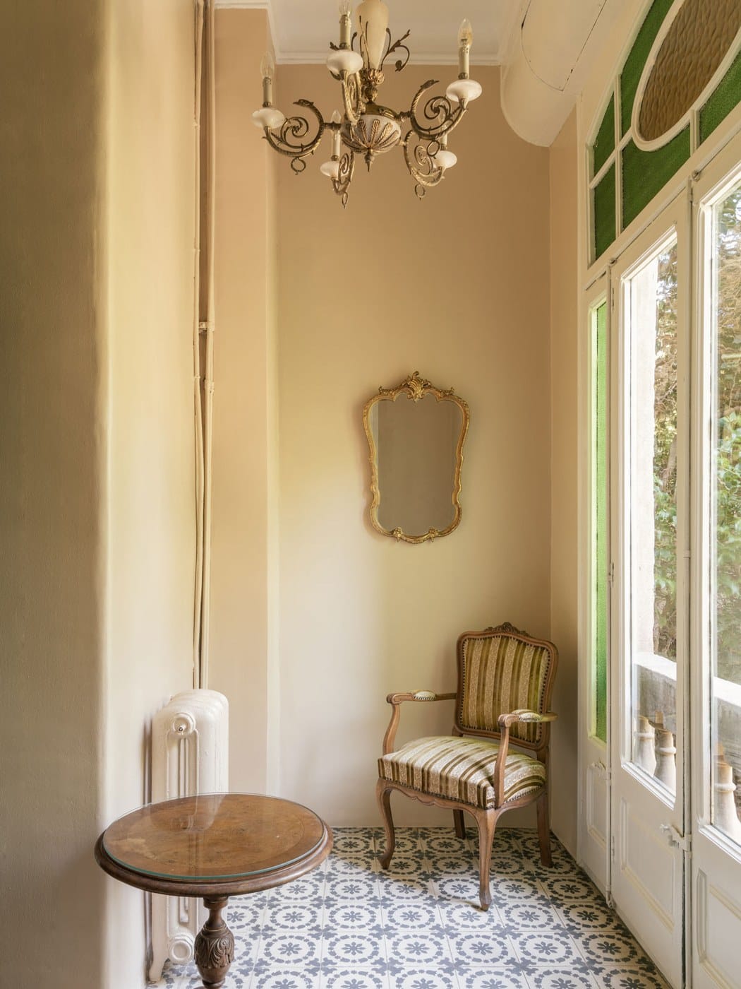 Sala com lustre, espelho dourado e piso de ladrilho hidráulico padronado