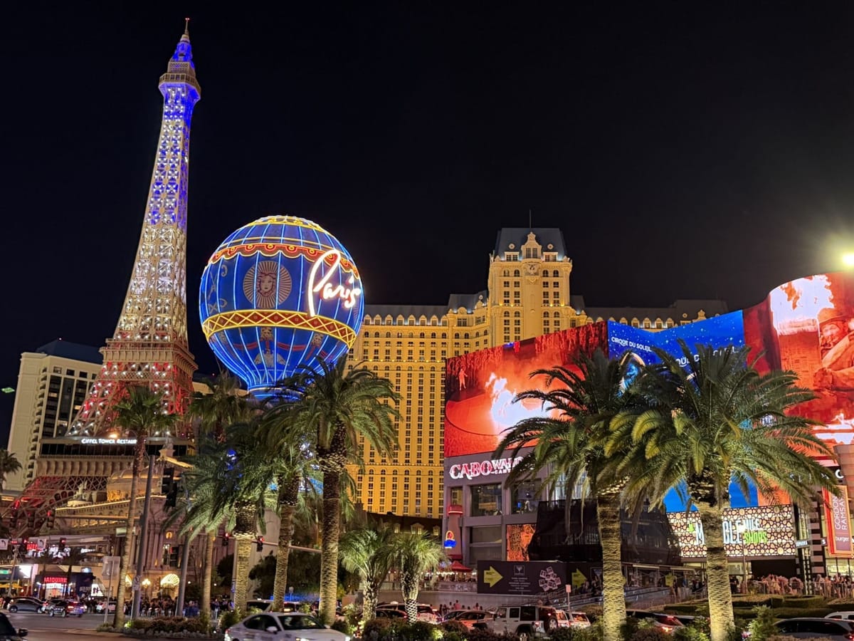 Vista noturna da Las Vegas Strip, com Torre Eiffel, balão Paris e hotéis iluminados