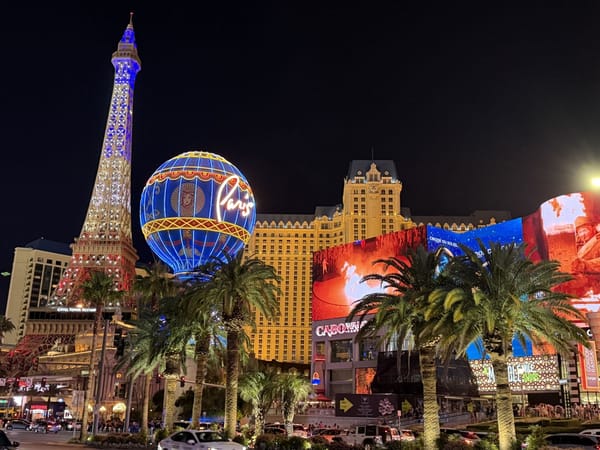 Vista noturna da Las Vegas Strip, com Torre Eiffel, balão Paris e hotéis iluminados