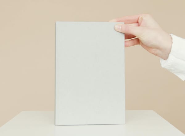 Mão segurando revestimento cinza minimalista sobre mesa clara, em fundo neutro bege