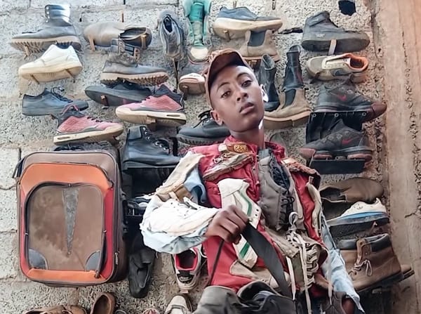 Kalu Putik, jovem vestindo roupa feita de materiais reciclados e sapatos reaproveitados, em frente a parede com calçados usados, destacando moda sustentável e criatividade no upcycling