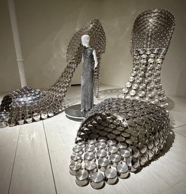 Instalação da artista Joana Vasconcelos na exposição "VENUS": esculturas metálicas em forma de sapatos gigantes cercam manequim com vestido prateado